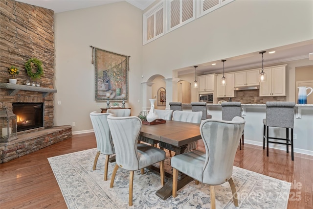 10620 Euclid Ave NW, Concord, NC 28027 - dining room with decorative columns, arched walkways, a fireplace, light wood-type flooring, and a high ceiling