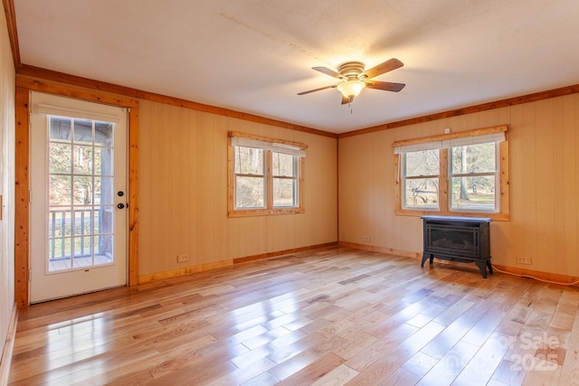 7150 Yellow Creek Rd, Robbinsville, NC 28771 - empty room featuring a wood stove, healthy amount of natural light, light wood-type flooring, a ceiling fan, and wood walls