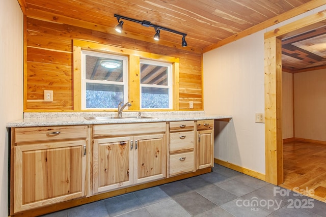 7150 Yellow Creek Rd, Robbinsville, NC 28771 - kitchen with rail lighting, a sink, wooden walls, dark tile patterned floors, and light brown cabinets