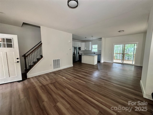 206 Cascade Ridge Rd, Fairview, NC 28730 - unfurnished living room featuring dark wood-style flooring, baseboards, stairway, and a sink