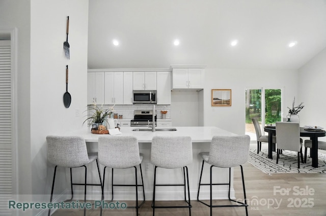 2116A Glenwood St, Kannapolis, NC 28083 - kitchen featuring appliances with stainless steel finishes, backsplash, a breakfast bar area, a peninsula, and white cabinetry