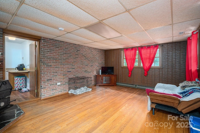 3120 7th Street Dr NE, Hickory, NC 28601 - living area featuring a paneled ceiling, a baseboard heating unit, wood finished floors, and brick wall