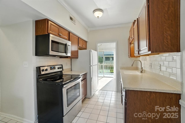 5947 Quail Hollow Rd Unit A, Charlotte, NC 28210 - kitchen featuring appliances with stainless steel finishes, light tile patterned flooring, light countertops, backsplash, and ornamental molding