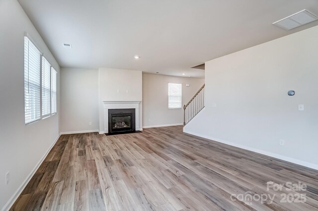2648 Tillman St, Monroe, NC 28112 - unfurnished living room featuring wood finished floors, a fireplace with flush hearth, baseboards, stairs, and recessed lighting