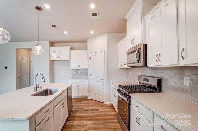 2648 Tillman St, Monroe, NC 28112 - kitchen with stainless steel appliances, a sink, light wood-style flooring, light countertops, and decorative light fixtures
