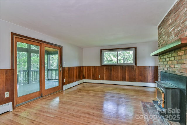 5 Old Cove Rd, Black Mountain, NC 28711 - unfurnished living room featuring a wainscoted wall, wood finished floors, a baseboard radiator, wood walls, and a wood stove