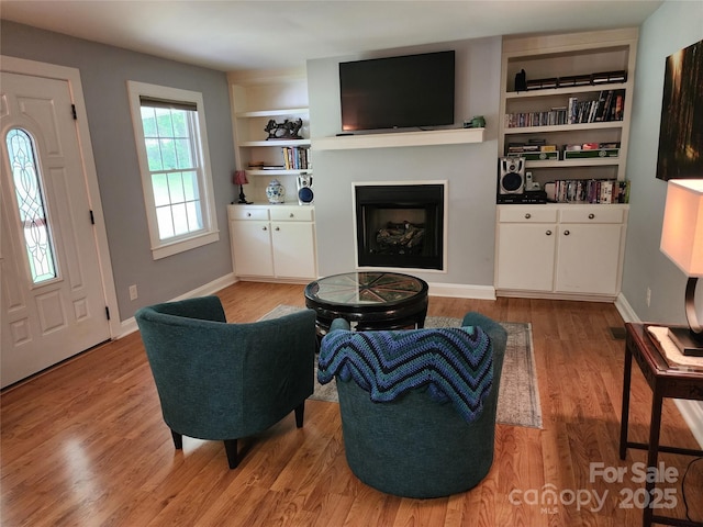 2904 E Brocktown Rd, Moravian Falls, NC 28654 - living room featuring light wood-type flooring, a fireplace, built in shelves, and baseboards