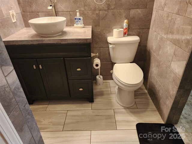 2904 E Brocktown Rd, Moravian Falls, NC 28654 - half bathroom featuring vanity, toilet, tile walls, and tile patterned flooring