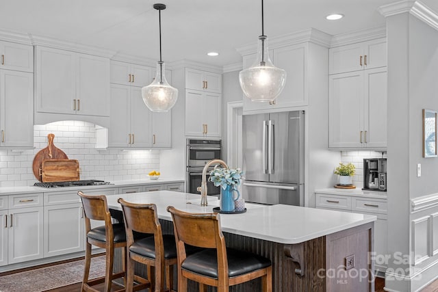 224 Hidden Meadows Dr, Mooresville, NC 28117 - kitchen with appliances with stainless steel finishes, white cabinets, light countertops, an island with sink, and tasteful backsplash