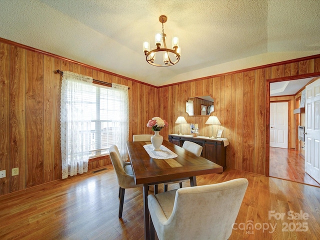 4115 Jenkins Rd, Marshville, NC 28103 - dining area with a chandelier, wood walls, a textured ceiling, light wood-style flooring, and vaulted ceiling