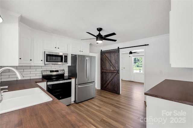 5323 Flat Creek Rd, Heath Springs, SC 29058 - kitchen featuring appliances with stainless steel finishes, dark countertops, ceiling fan, a barn door, and crown molding