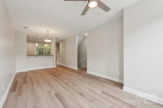 1126 Dean Hall Ln, Matthews, NC 28105 - unfurnished living room with light wood finished floors, baseboards, a ceiling fan, and stairway