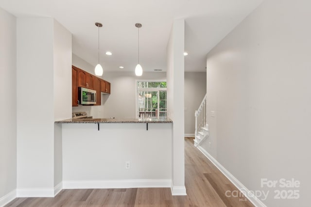 1126 Dean Hall Ln, Matthews, NC 28105 - kitchen featuring stainless steel microwave, dark stone countertops, light wood-style floors, a breakfast bar, and recessed lighting