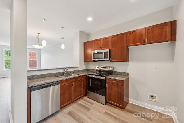 1126 Dean Hall Ln, Matthews, NC 28105 - kitchen featuring stainless steel appliances, a sink, light wood finished floors, decorative light fixtures, and dark stone countertops
