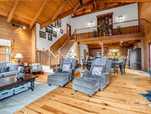 120 Rocky Mountain Dr, Lake Lure, NC 28746 - living room featuring high vaulted ceiling, wood walls, stairs, light wood-style flooring, and a wooden ceiling with exposed beams