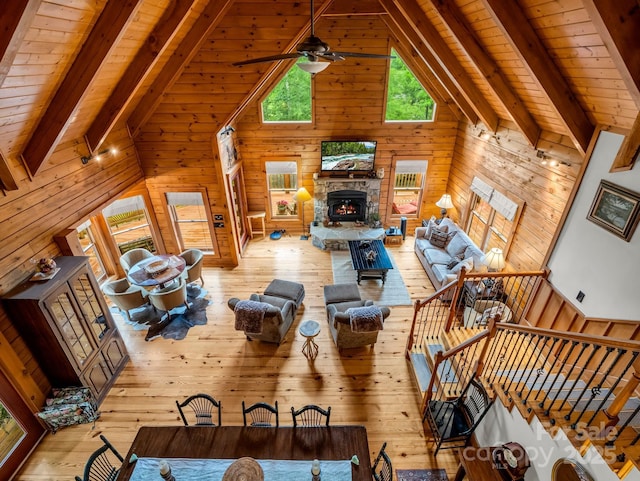 120 Rocky Mountain Dr, Lake Lure, NC 28746 - living room with light wood-style flooring, wooden walls, wooden ceiling, a ceiling fan, and a stone fireplace