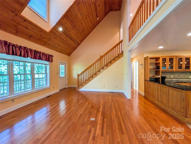 355 Rosewood Ln, Burnsville, NC 28714 - unfurnished living room featuring stairs, high vaulted ceiling, baseboards, light wood-style flooring, and a skylight
