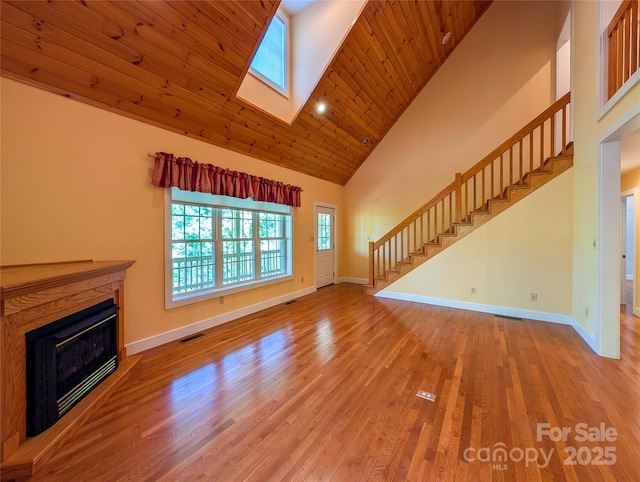 355 Rosewood Ln, Burnsville, NC 28714 - unfurnished living room featuring stairway, high vaulted ceiling, baseboards, a glass covered fireplace, and wood finished floors