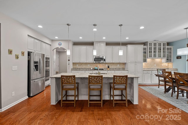 7339 Millstone Cir SW, Concord, NC 28025 - kitchen with appliances with stainless steel finishes, tasteful backsplash, wood finished floors, white cabinets, and an island with sink