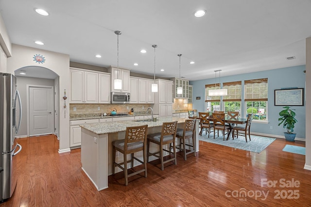 7339 Millstone Cir SW, Concord, NC 28025 - kitchen with stainless steel appliances, baseboards, arched walkways, white cabinetry, and tasteful backsplash