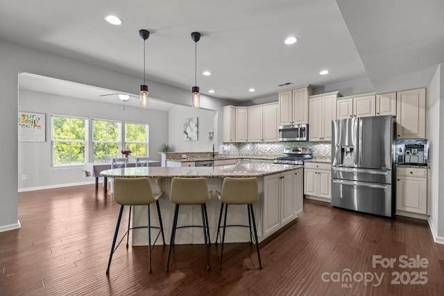 1300 Yellow Springs Dr, Indian Land, SC 29707 - kitchen with appliances with stainless steel finishes, a kitchen bar, tasteful backsplash, light stone countertops, and pendant lighting