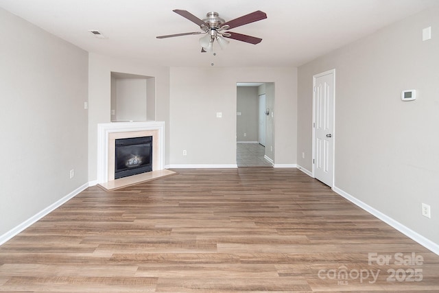 8432 Spirea Ct, Charlotte, NC 28215 - unfurnished living room featuring ceiling fan, a glass covered fireplace, baseboards, and light wood-style flooring