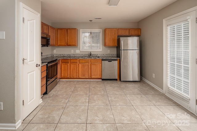 8432 Spirea Ct, Charlotte, NC 28215 - kitchen with stainless steel appliances, a sink, light tile patterned flooring, stone countertops, and brown cabinets
