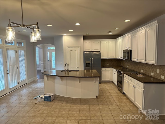 10715 Tom Short Rd, Charlotte, NC 28277 - kitchen featuring stainless steel appliances, arched walkways, dark countertops, light tile patterned floors, and recessed lighting
