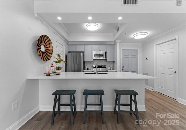 300 W Fifth St Unit 509, Charlotte, NC 28202 - kitchen with stainless steel appliances, a breakfast bar area, dark wood-type flooring, light countertops, and crown molding