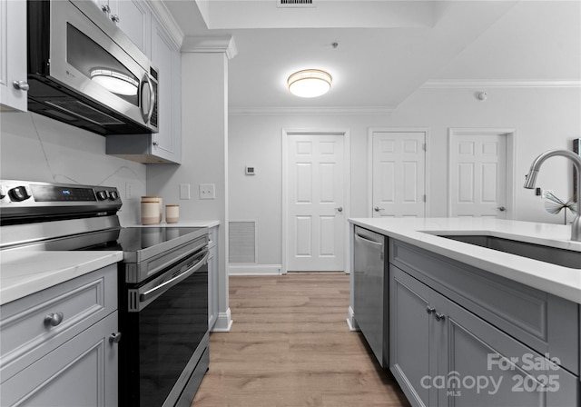 300 W Fifth St Unit 509, Charlotte, NC 28202 - kitchen featuring stainless steel appliances, a sink, gray cabinetry, crown molding, and light countertops