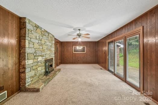 125 Merrill Rd, Fletcher, NC 28732 - unfurnished living room with wooden walls, ceiling fan, light colored carpet, a textured ceiling, and a fireplace