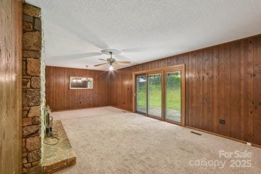 125 Merrill Rd, Fletcher, NC 28732 - unfurnished living room featuring ceiling fan, carpet, a textured ceiling, and wood walls