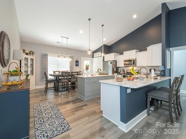 805 Brookmont Ave, Salisbury, NC 28146 - kitchen with stainless steel appliances, a peninsula, light wood-type flooring, high vaulted ceiling, and pendant lighting