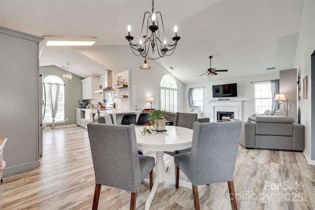4712 Avalon Forest Ln, Charlotte, NC 28269 - dining space with ceiling fan, vaulted ceiling, a fireplace, a chandelier, and light wood-style flooring
