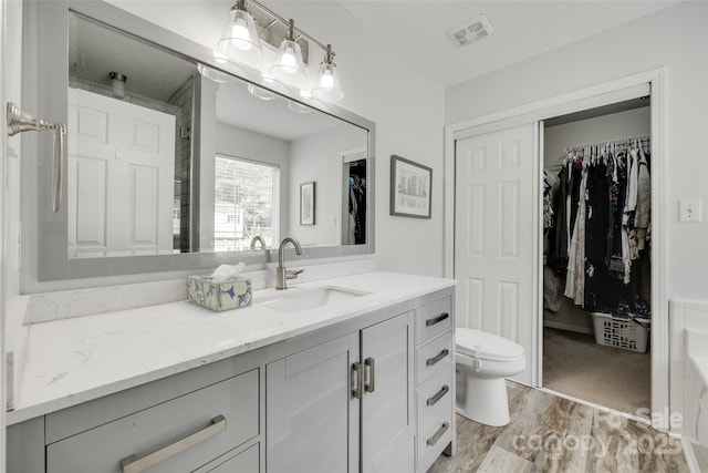 4712 Avalon Forest Ln, Charlotte, NC 28269 - bathroom featuring vanity, a walk in closet, wood finished floors, and toilet