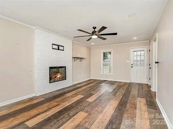 3572 Heather Ln, Gastonia, NC 28056 - unfurnished living room featuring wood finished floors, ornamental molding, ceiling fan, baseboards, and a brick fireplace