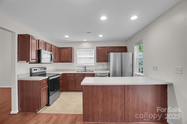 5237 Ficus Tree Ln, Charlotte, NC 28215 - kitchen with appliances with stainless steel finishes, a peninsula, light countertops, recessed lighting, and light wood-style flooring