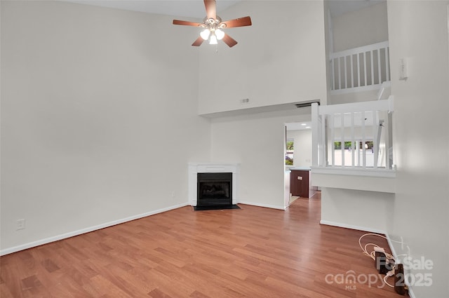 5237 Ficus Tree Ln, Charlotte, NC 28215 - unfurnished living room with a towering ceiling, a ceiling fan, wood finished floors, and a fireplace with flush hearth