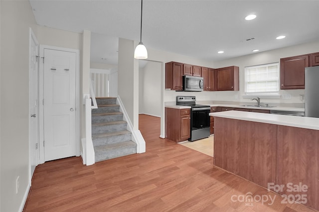 5237 Ficus Tree Ln, Charlotte, NC 28215 - kitchen featuring stainless steel appliances, light countertops, light wood-type flooring, decorative light fixtures, and recessed lighting