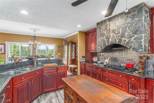 1706 Rock House Cove Rd, Clyde, NC 28721 - kitchen with a sink, reddish brown cabinets, gas stovetop, a textured ceiling, and crown molding