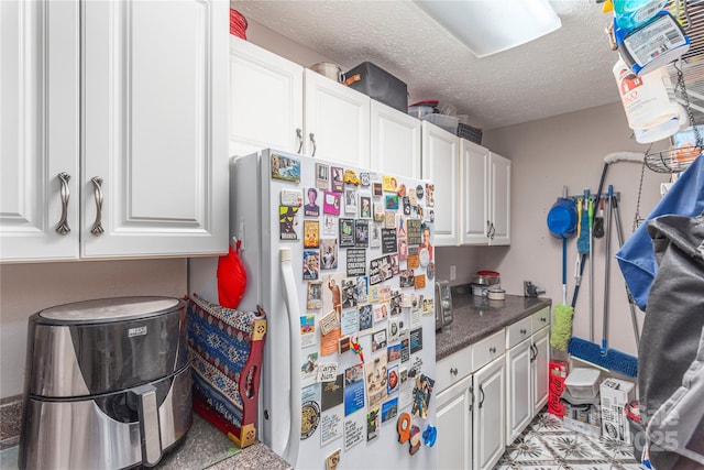 1706 Rock House Cove Rd, Clyde, NC 28721 - kitchen with freestanding refrigerator, white cabinets, a textured ceiling, and dark countertops