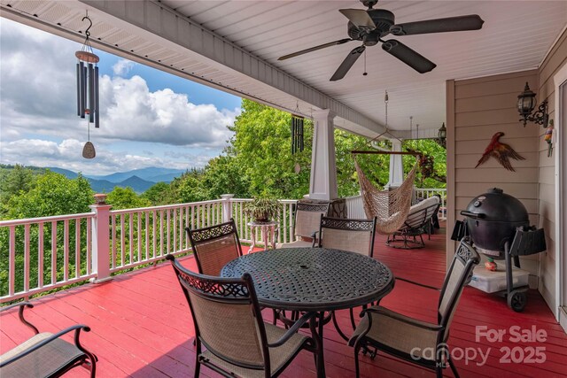 1706 Rock House Cove Rd, Clyde, NC 28721 - wooden deck with outdoor dining area, a ceiling fan, and a mountain view