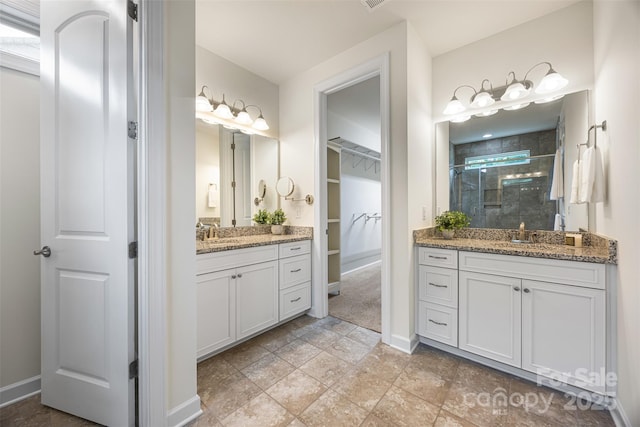 1284 Independence St, Fort Mill, SC 29708 - bathroom with a shower stall, two vanities, a walk in closet, baseboards, and stone finish flooring