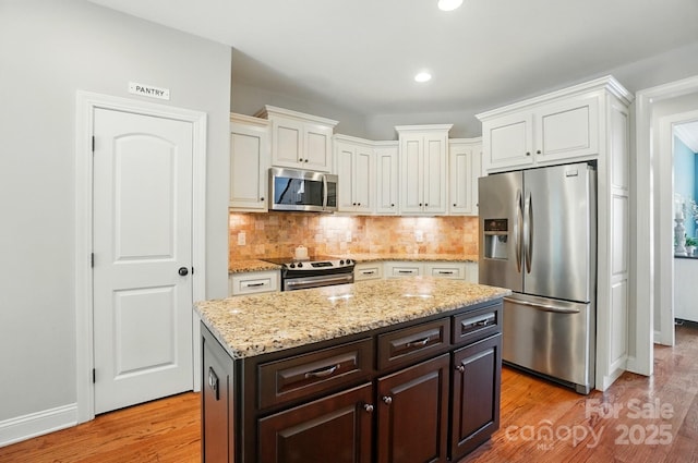 7006 Nesbit Rd, Waxhaw, NC 28173 - kitchen featuring appliances with stainless steel finishes, light wood-style floors, white cabinets, decorative backsplash, and recessed lighting