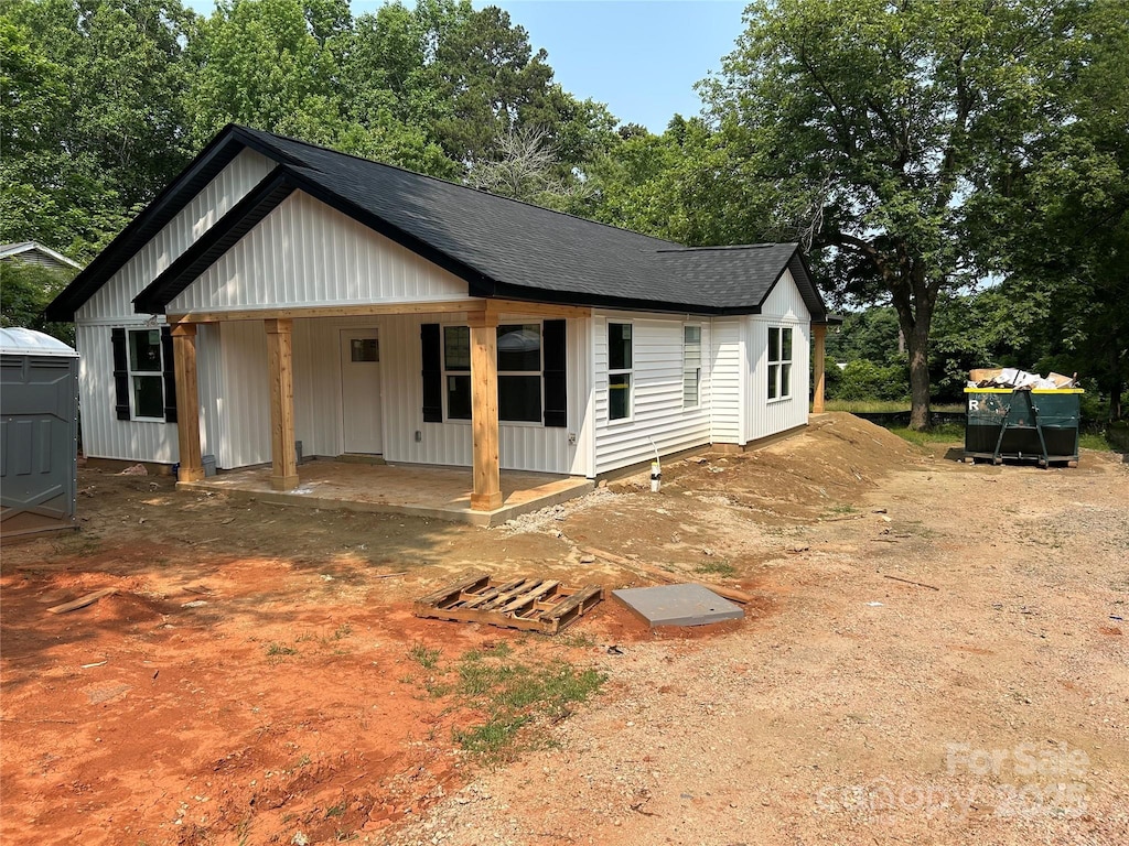 807 S Bostian St, China Grove, NC 28023 - view of front facade with board and batten siding, a shingled roof, and covered porch
