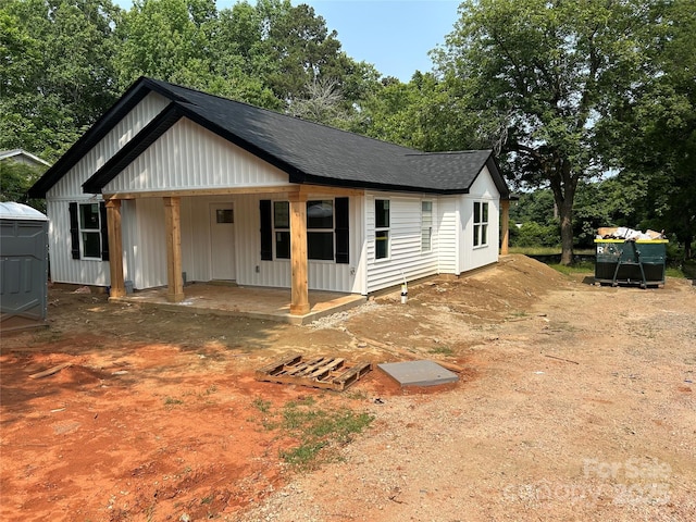 807 S Bostian St, China Grove, NC 28023 - view of front facade with board and batten siding, a shingled roof, and covered porch