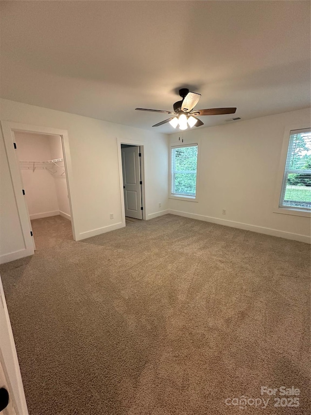 807 S Bostian St, China Grove, NC 28023 - unfurnished bedroom with multiple windows, carpet, a walk in closet, and a ceiling fan