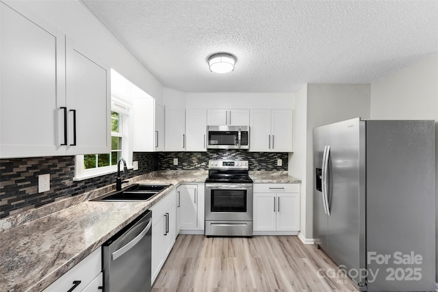 103A N Tracy St, Kings Mountain, NC 28086 - kitchen with appliances with stainless steel finishes, a sink, light wood-style floors, white cabinets, and a textured ceiling