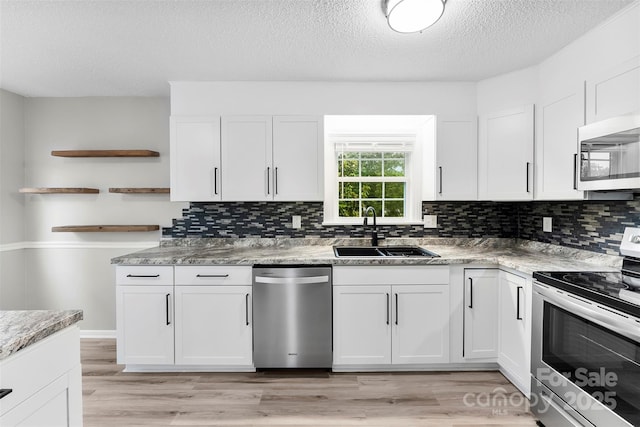 103A N Tracy St, Kings Mountain, NC 28086 - kitchen with appliances with stainless steel finishes, a sink, open shelves, white cabinets, and light wood-style floors