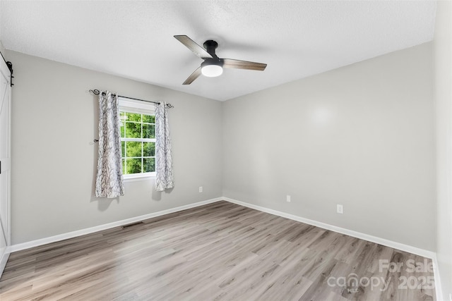103A N Tracy St, Kings Mountain, NC 28086 - spare room with light wood finished floors, a ceiling fan, baseboards, a barn door, and a textured ceiling